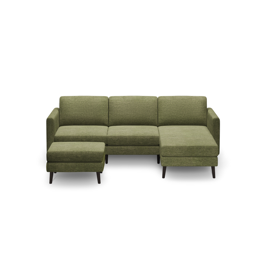 Green fabric L-shaped sectional sofa with chaise lounge and matching ottoman, featuring wooden legs.