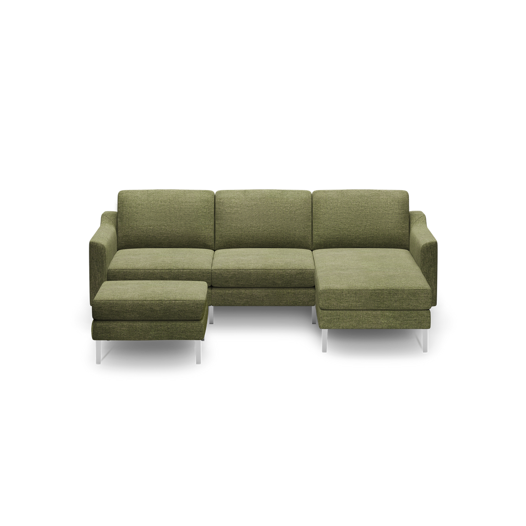 Green upholstered modern sectional sofa with chaise lounge on the right and metal legs on a black background.