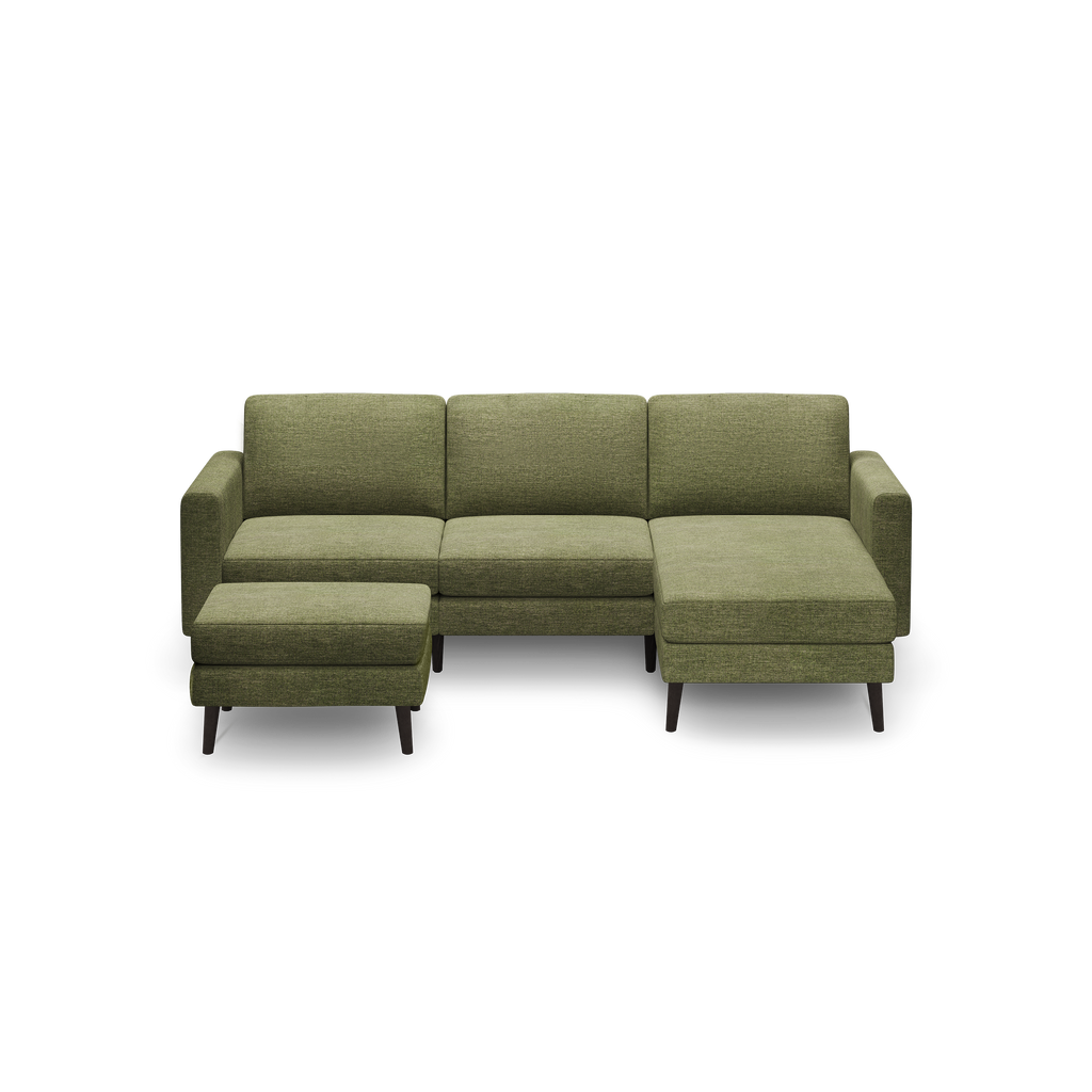 Modern L-shaped olive green fabric sofa with three-seat cushions, low backrest, armrests, and dark wooden legs, isolated on black background.