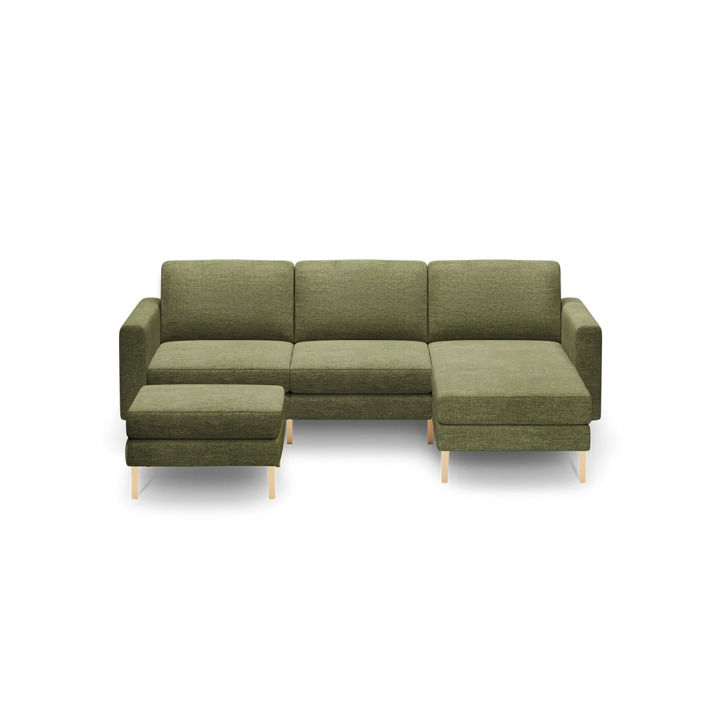 Olive green fabric sectional sofa with wooden legs, featuring a chaise lounge on the right and a matching ottoman on the left.