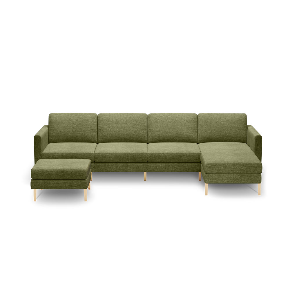 Modern olive green fabric sectional sofa with chaise lounge on right and separate ottoman, supported by light wooden legs.