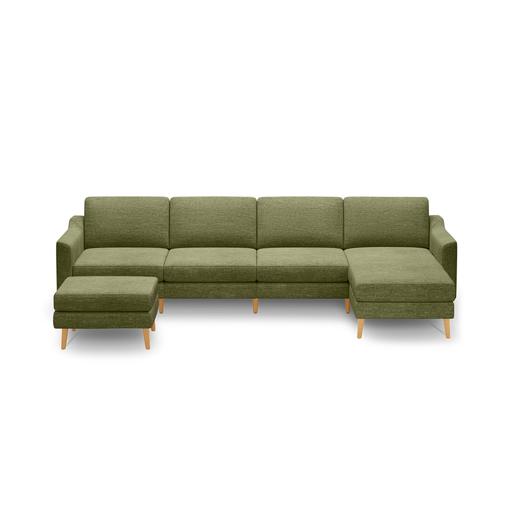 Green fabric sectional sofa with chaise lounge and matching ottoman, supported by light wooden legs.