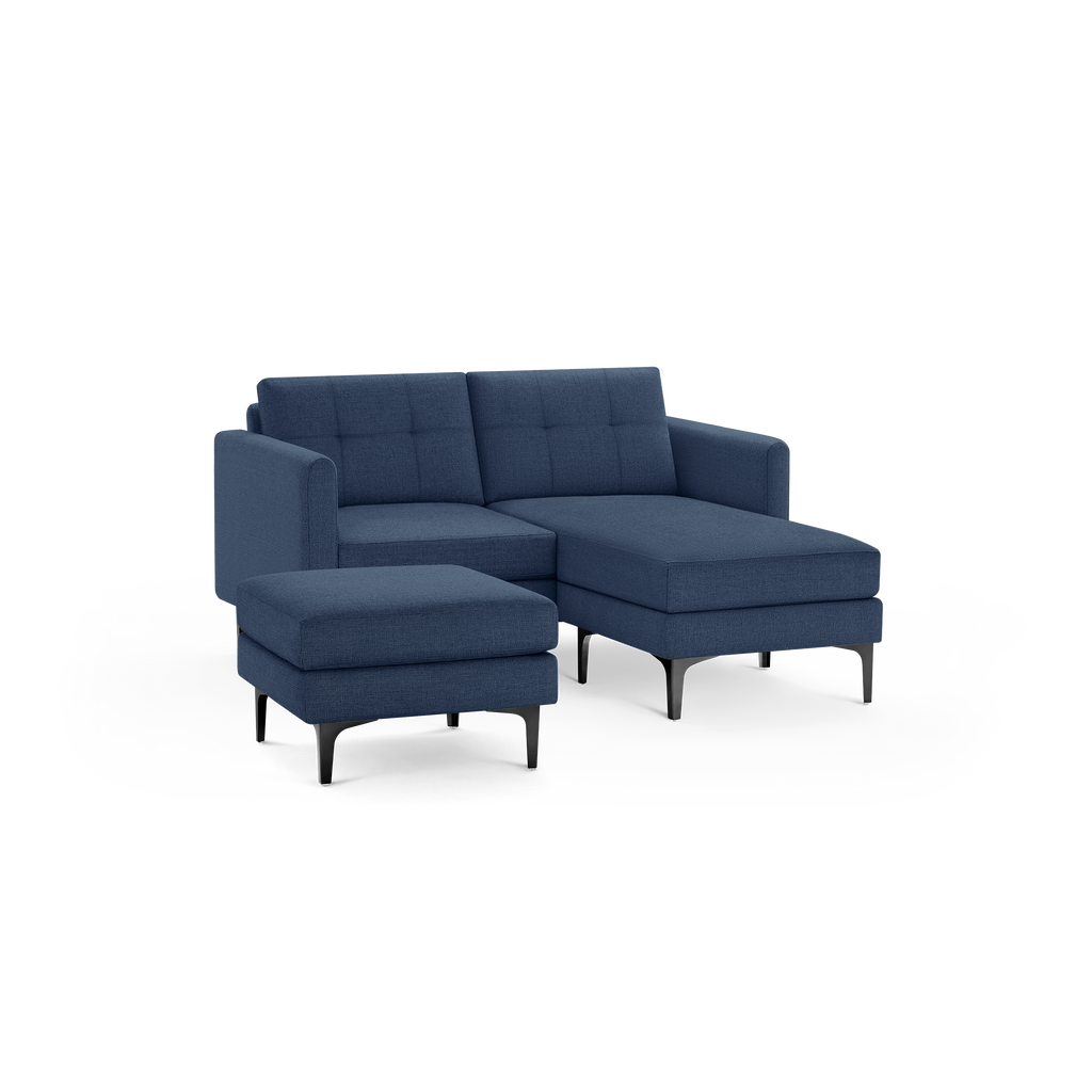 Modern navy blue sectional sofa with an attached chaise lounge and separate matching ottoman, featuring tufted cushions and black metal legs.