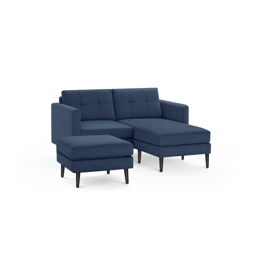 Modern navy blue fabric sectional sofa with tufted back cushions, chaise lounge, and matching ottoman on black tapered legs.