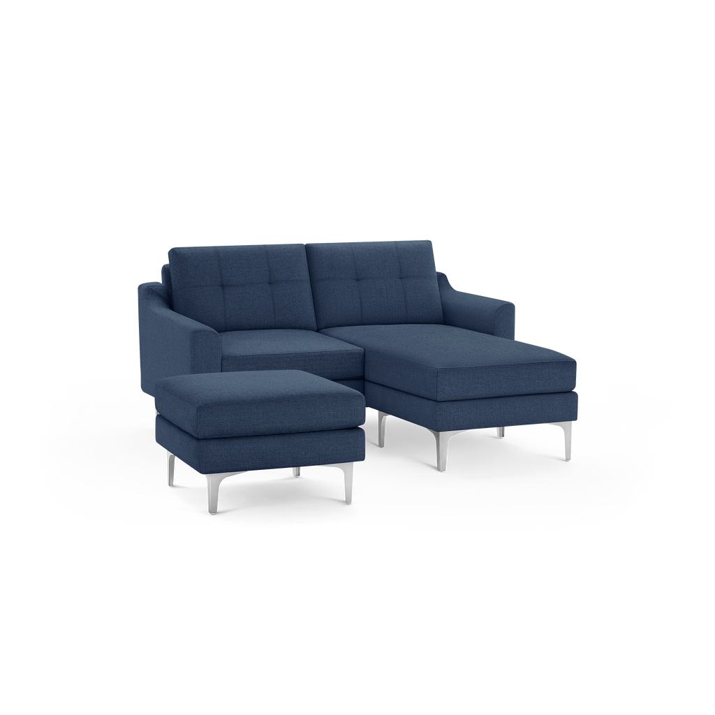 Modern navy blue fabric sectional sofa with tufted back cushions and matching ottoman, supported by sleek silver metal legs.