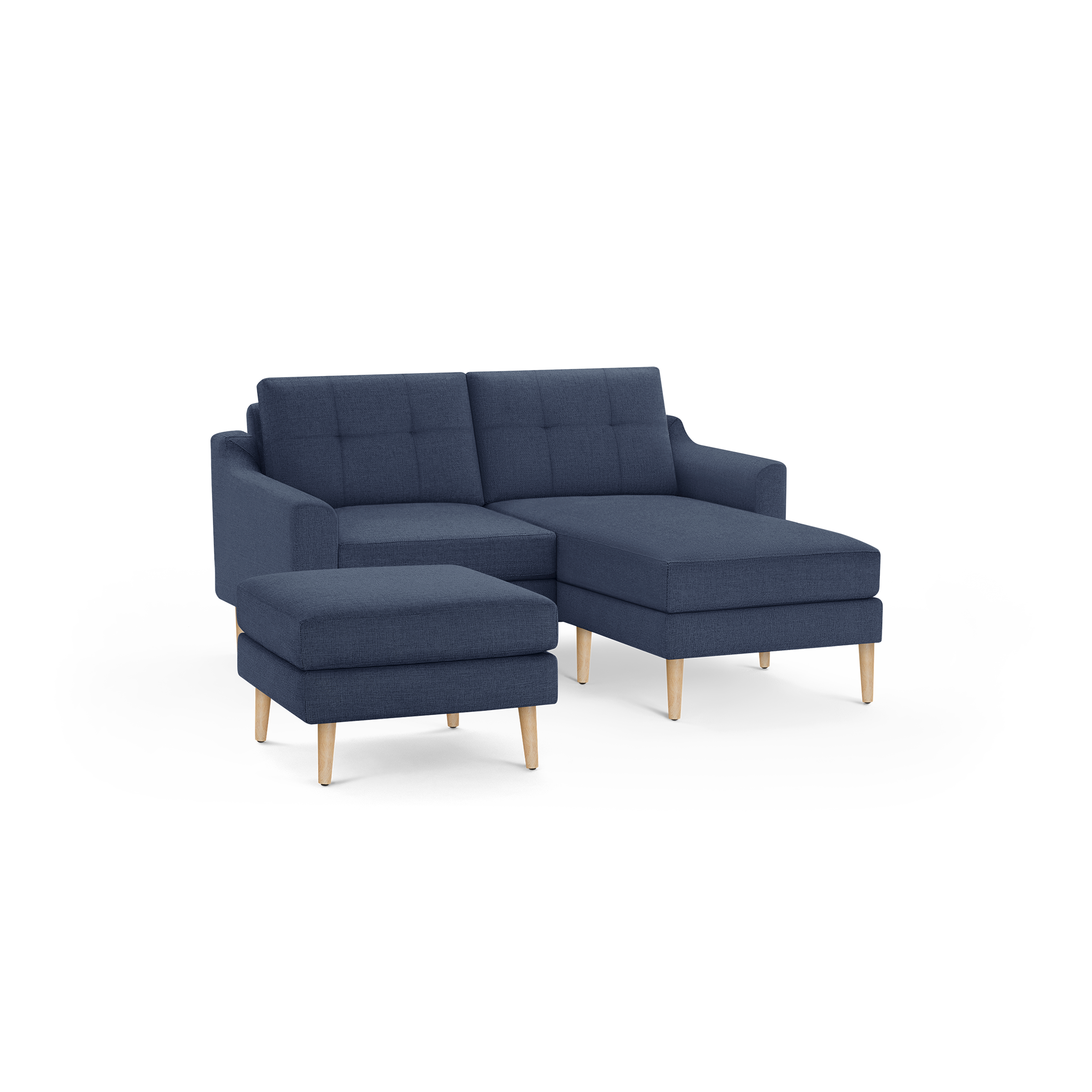 Modern navy blue sectional sofa with tufted back cushions, wooden legs, and a matching ottoman on isolated background.