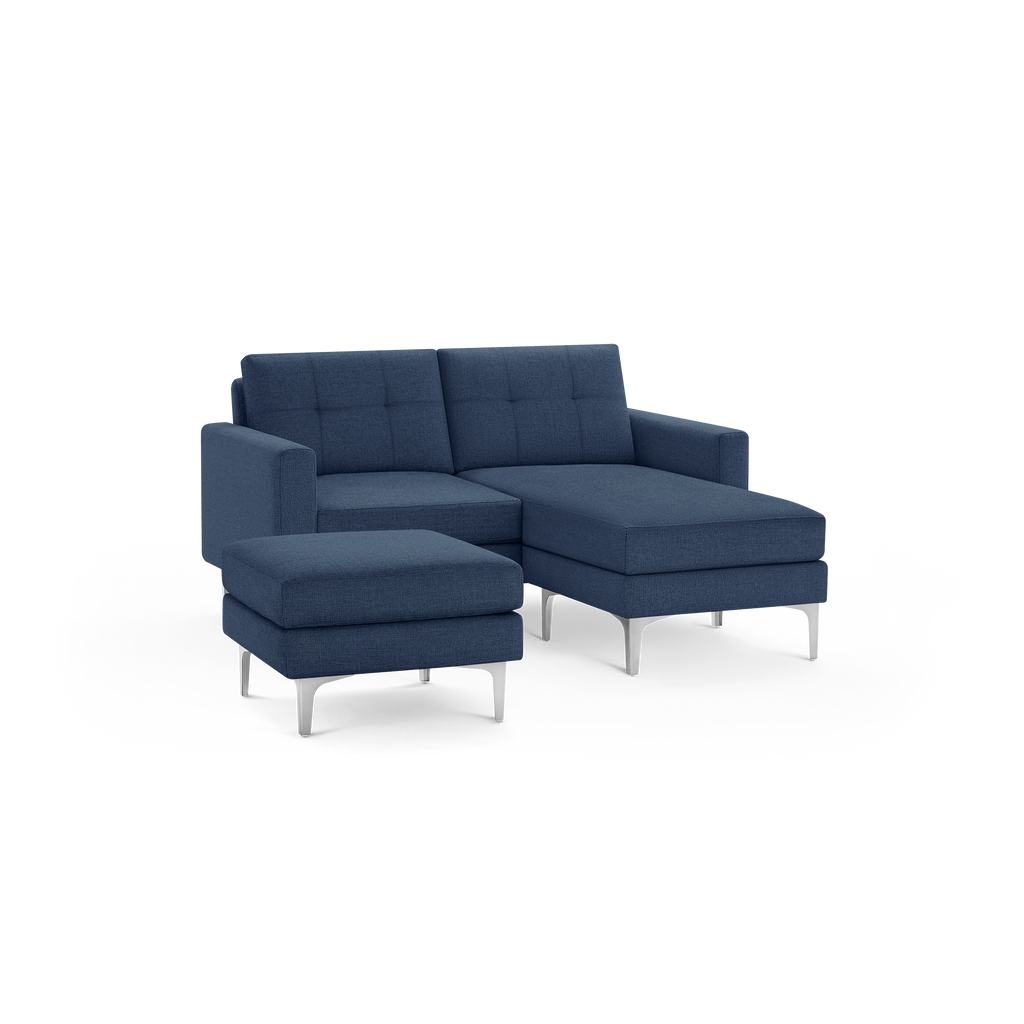 Modern navy blue upholstered sectional sofa with tufted backrest and separate ottoman on sleek silver legs.