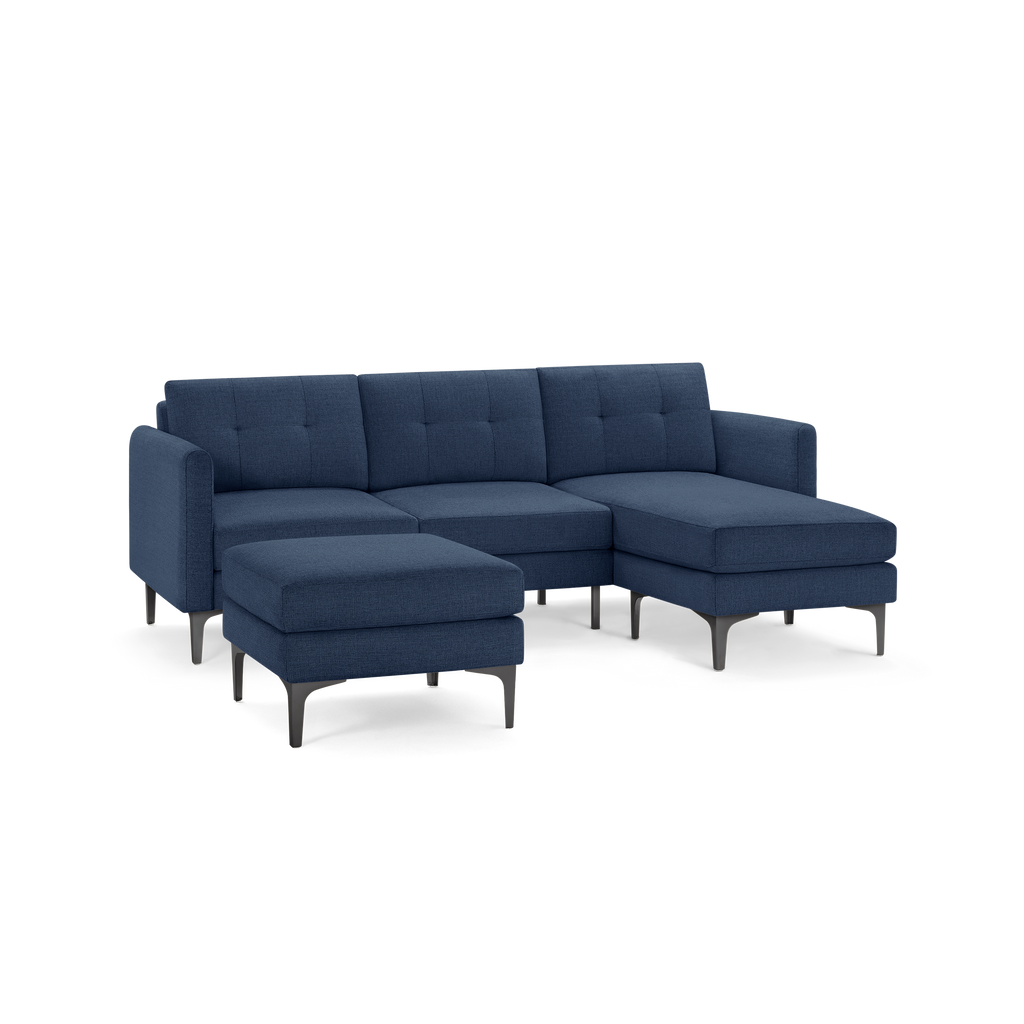 Modern navy blue sectional sofa with metal legs, tufted back cushions, and a matching ottoman.