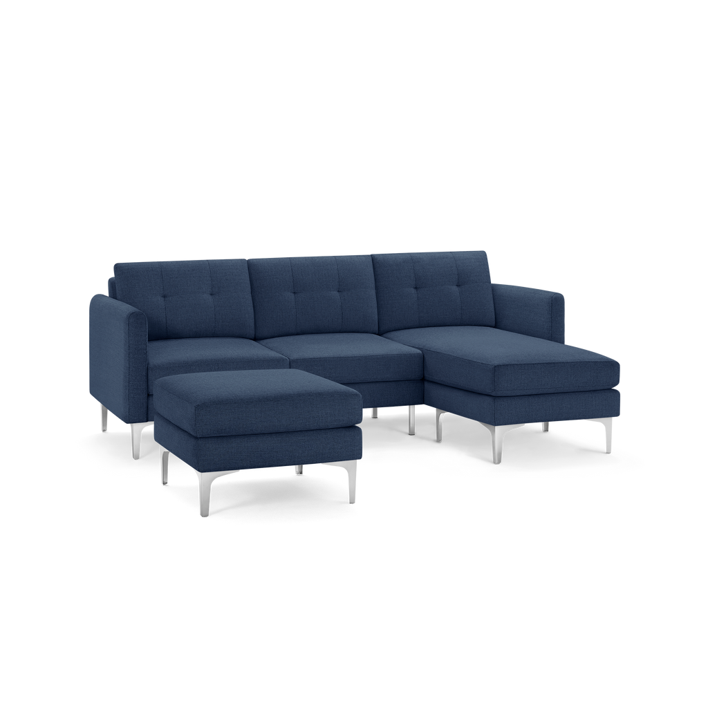 Modern navy blue sectional sofa with tufted back cushions, metal legs, and a matching ottoman.