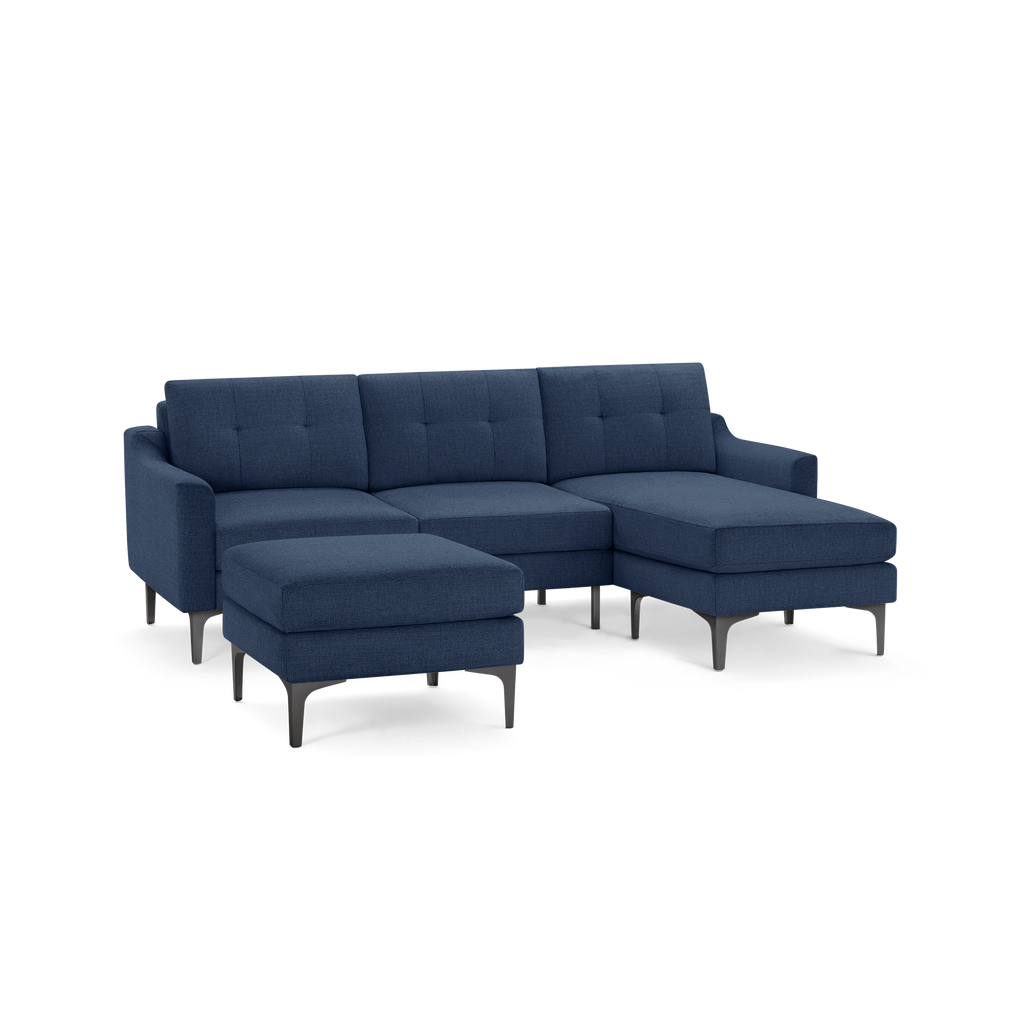 Dark blue modern sectional sofa with chaise lounge and matching ottoman, featuring tufted cushions and slender metal legs.
