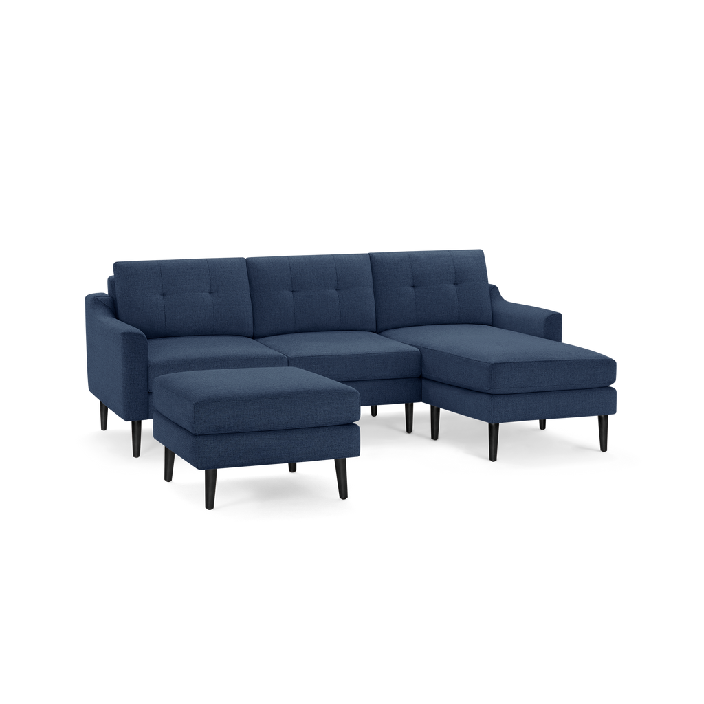 Modern navy blue sectional sofa with tufted back cushions, black tapered legs, and a matching ottoman on a white background.