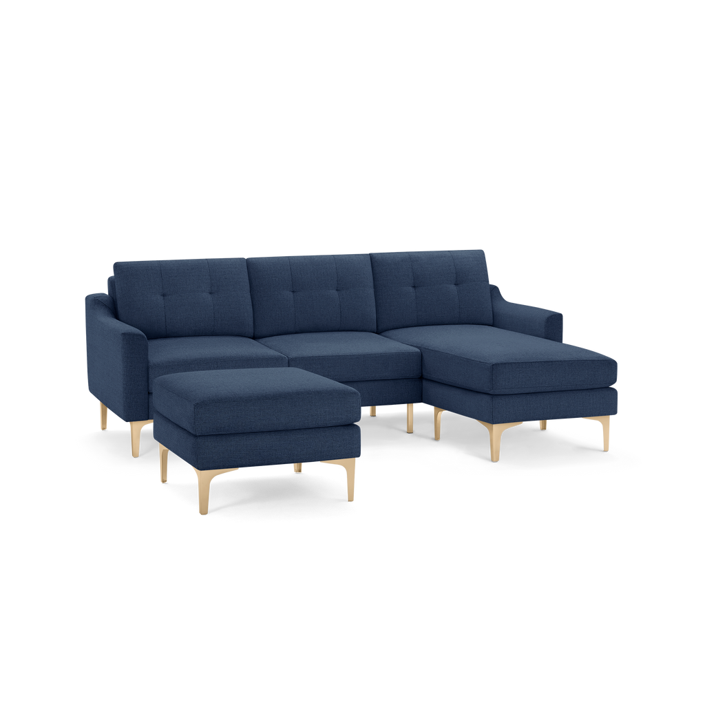 Modern navy blue sectional sofa with tufted cushions, wooden legs, and a matching ottoman.