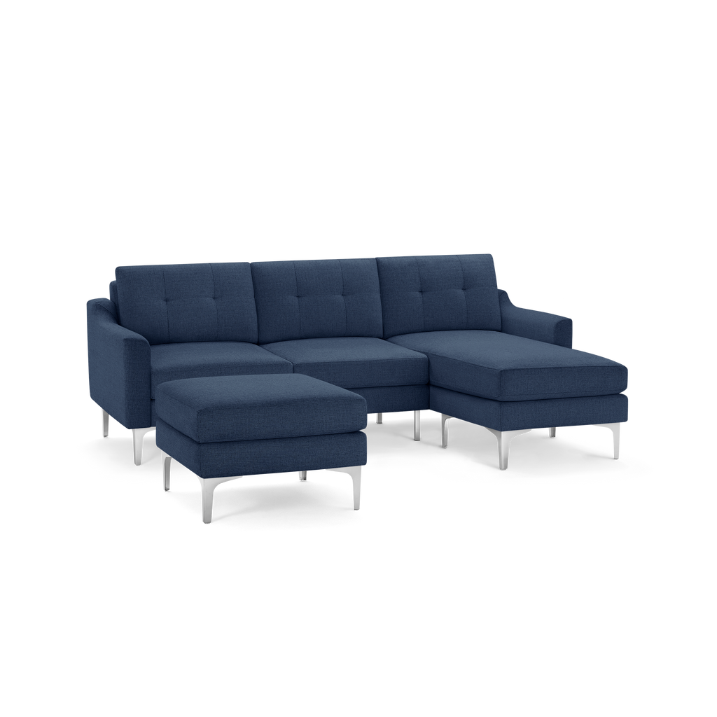 Modern navy blue sectional sofa with tufted cushions, metal legs, and a matching ottoman, isolated on white background.