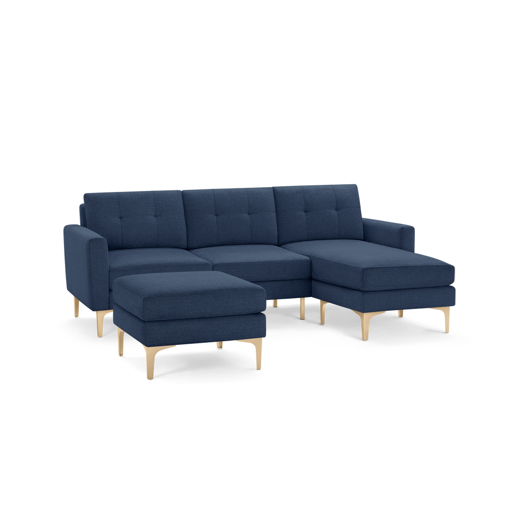 Modern navy blue sectional sofa with tufted cushions, wooden legs, and matching ottoman.
