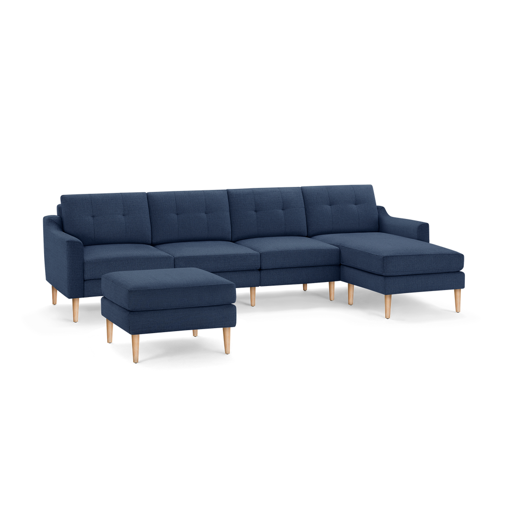 Modern navy blue sectional sofa with wooden legs, featuring tufted cushions and a matching ottoman.