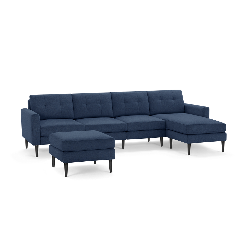 Modern navy blue sectional sofa with tufted back cushions, chaise lounge on right, and matching ottoman, featuring black tapered legs.