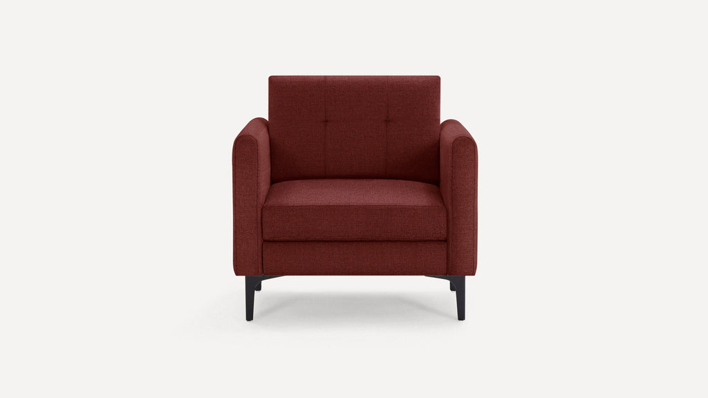 Front view of a modern, deep red upholstered armchair with tufted backrest and slim black legs on white background.