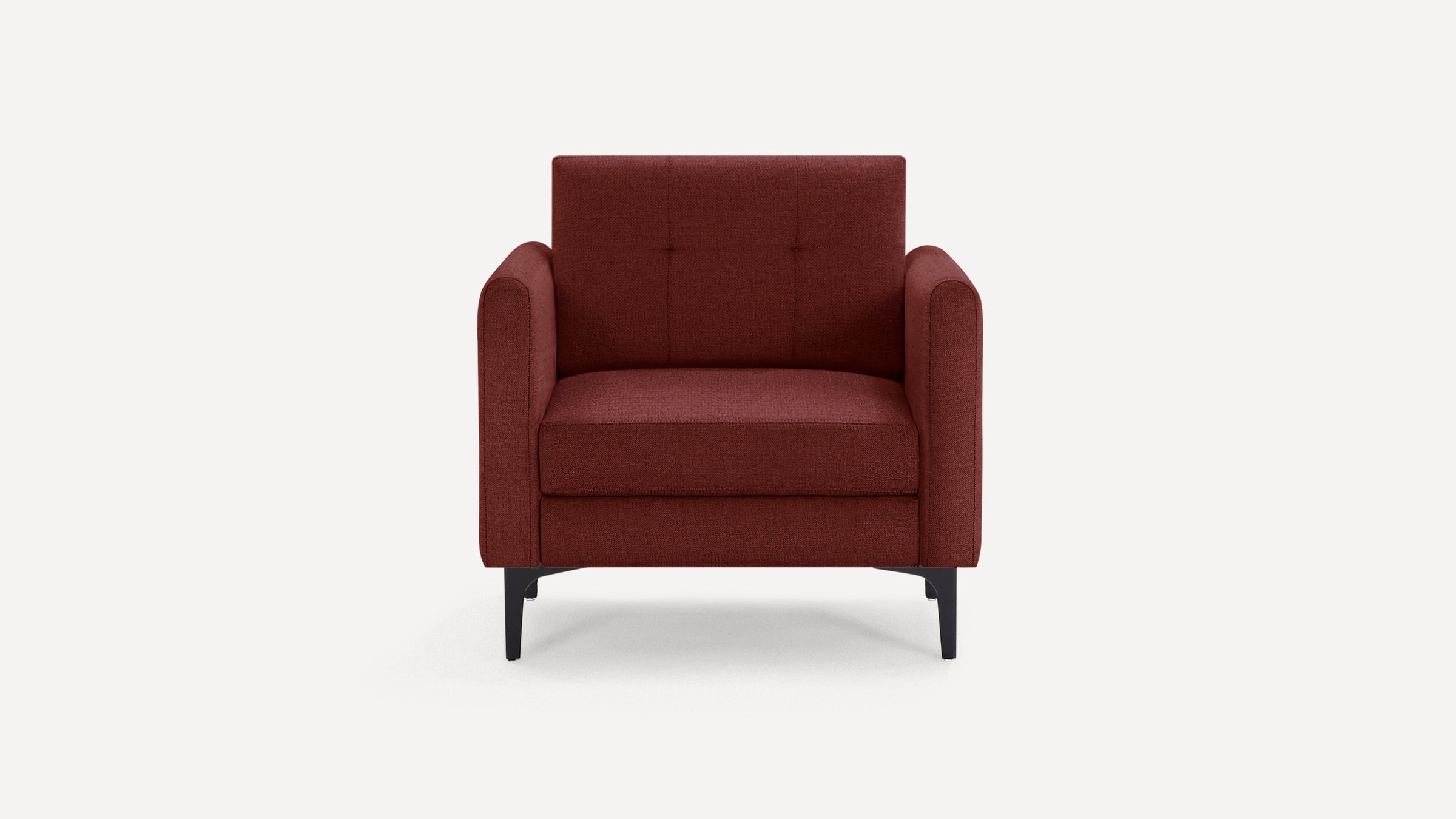 Front view of a modern, deep red upholstered armchair with tufted backrest and slim black legs on white background.
