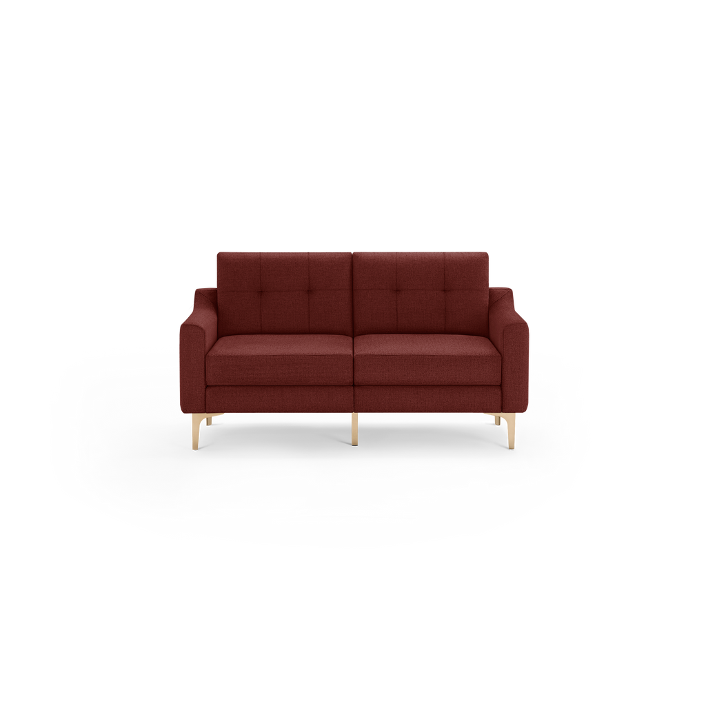 Modern two-seater sofa in deep red fabric with tufted back cushions and sleek light wooden legs, minimalist design.