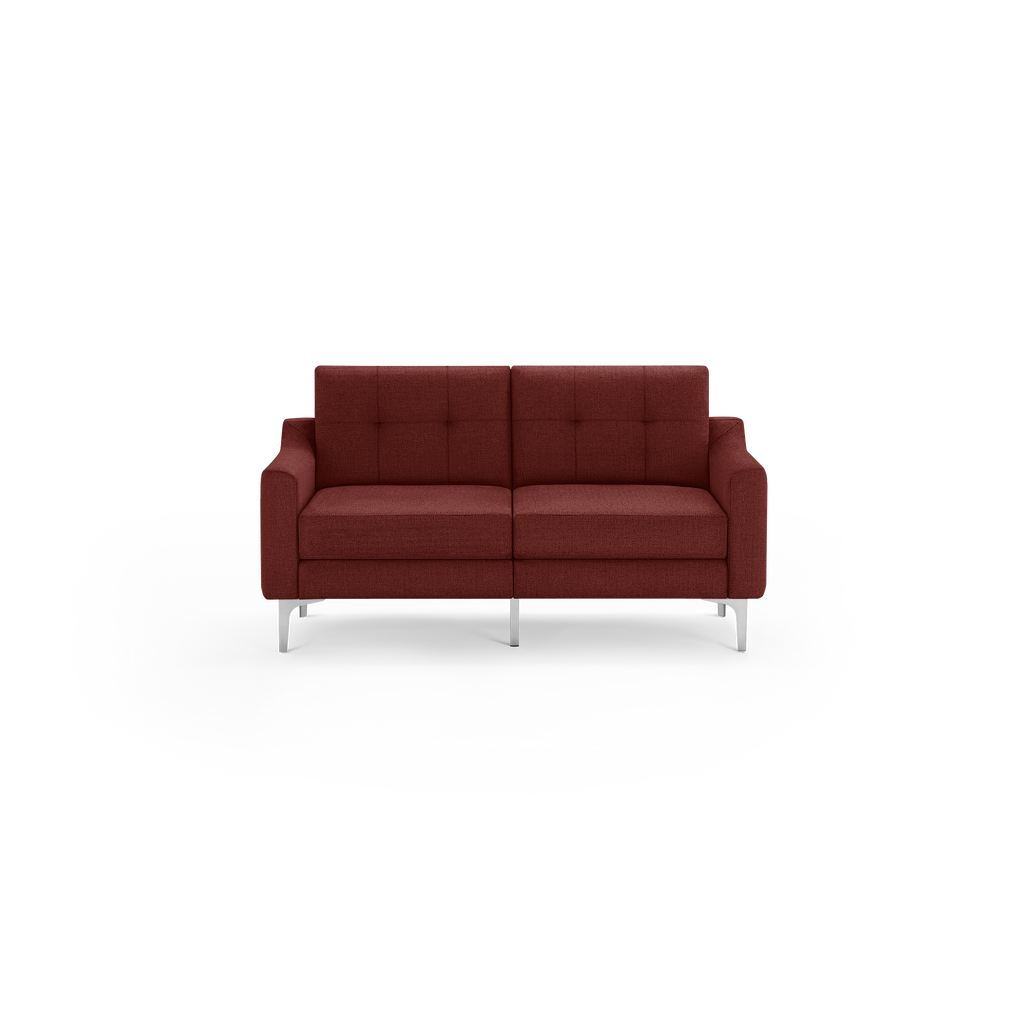 Modern two-seater sofa in dark red fabric with tufted back cushions and chrome metal legs, minimalist design.