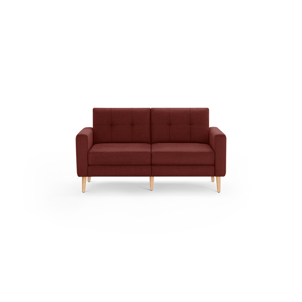 Modern mid-century style two-seater sofa in dark red fabric with tufted backrest and light wooden legs on a black background.