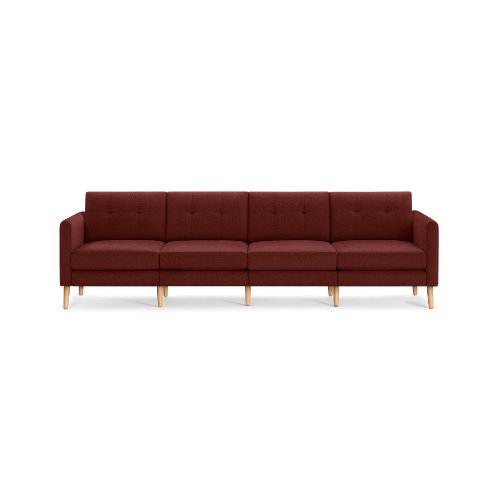 Modern four-seater sofa with deep red fabric upholstery, tufted back cushions, and light wooden legs, pictured against a transparent background.