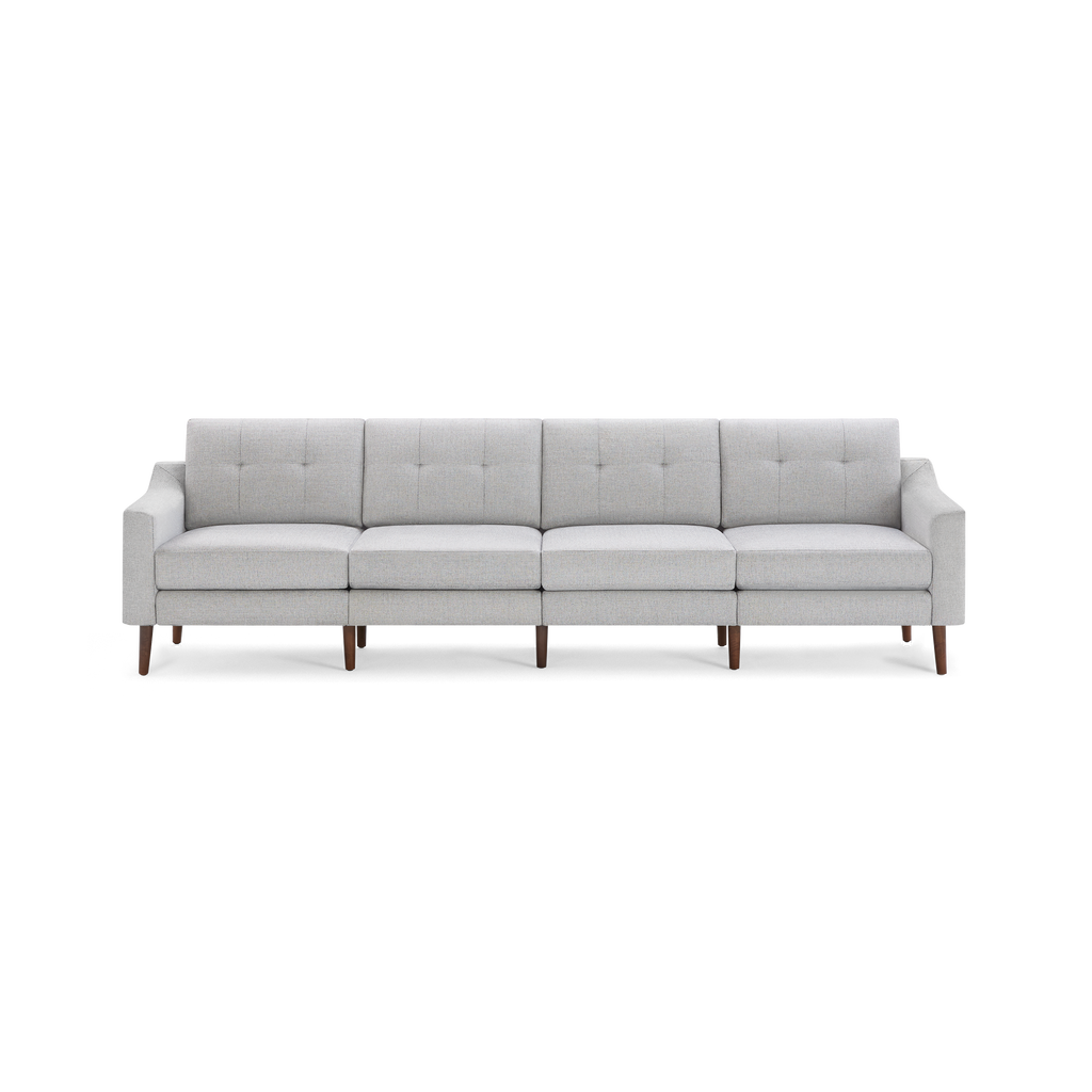 Light gray modern four-seater sofa with tufted backrest cushions and wooden tapered legs on a black background.