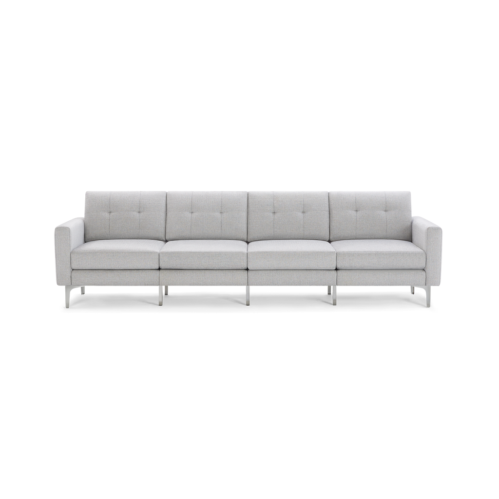 Modern light gray fabric four-seater sofa with tufted back cushions and slim silver metal legs, isolated on black background.