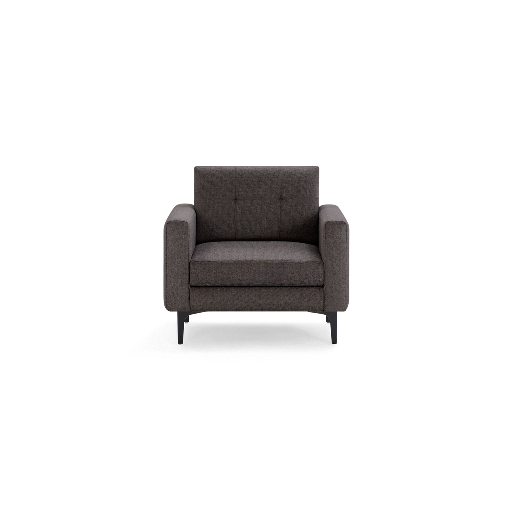 Modern dark gray upholstered armchair with straight arms, button-tufted backrest, and black tapered legs, isolated on black background.