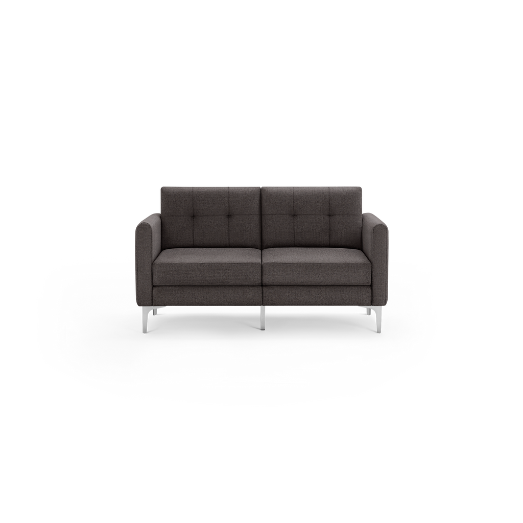 Modern dark gray upholstered two-seater sofa with tufted backrest, cushioned seats, and slim metal legs, shown against a black background.
