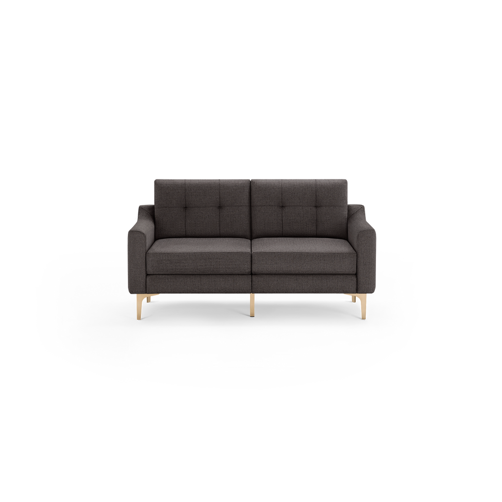 Dark gray upholstered two-seater sofa with tufted backrest, square arms, and wooden legs in light finish, isolated on black.