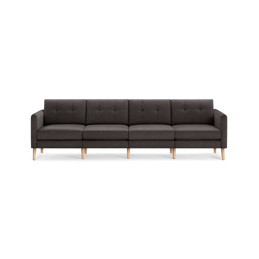 Dark gray fabric four-seater sofa with tufted backrests, straight arms, and light wooden legs in a modern minimalist design.