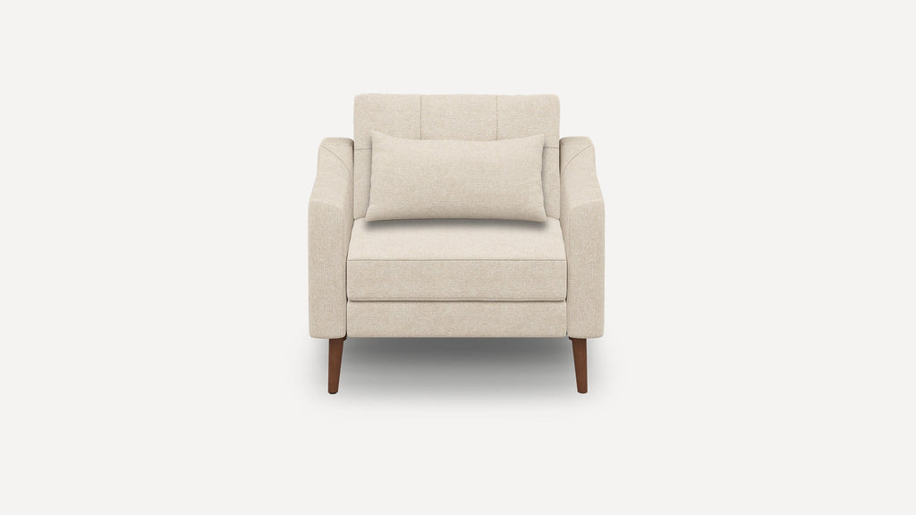 Beige upholstered armchair with a cushioned backrest and a matching lumbar pillow, supported by four wooden legs.