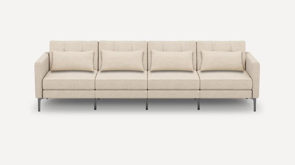 Modern beige four-seater sofa with clean lines, metal legs, and four rectangular matching throw pillows, shown on a white background.