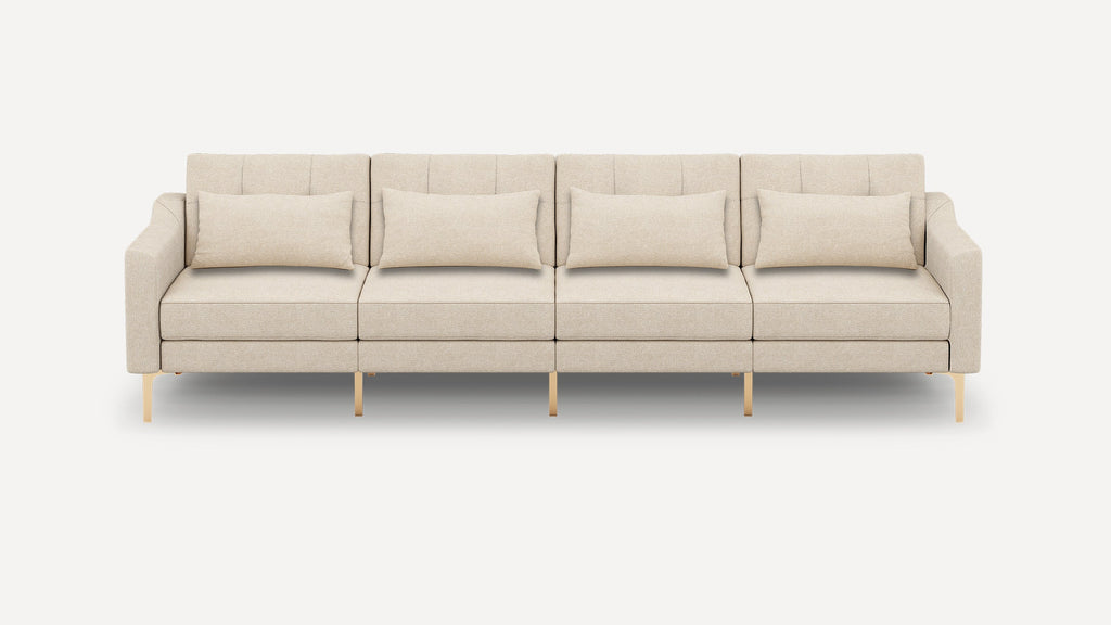 Beige modern four-seater sofa with clean lines, gold metal legs, and four matching lumbar pillows on a white background.