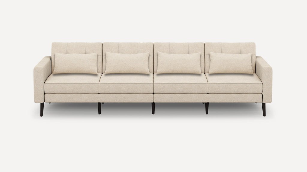 Beige four-seater sofa with clean lines, rectangular cushions, padded armrests, and dark tapered wooden legs on plain background.