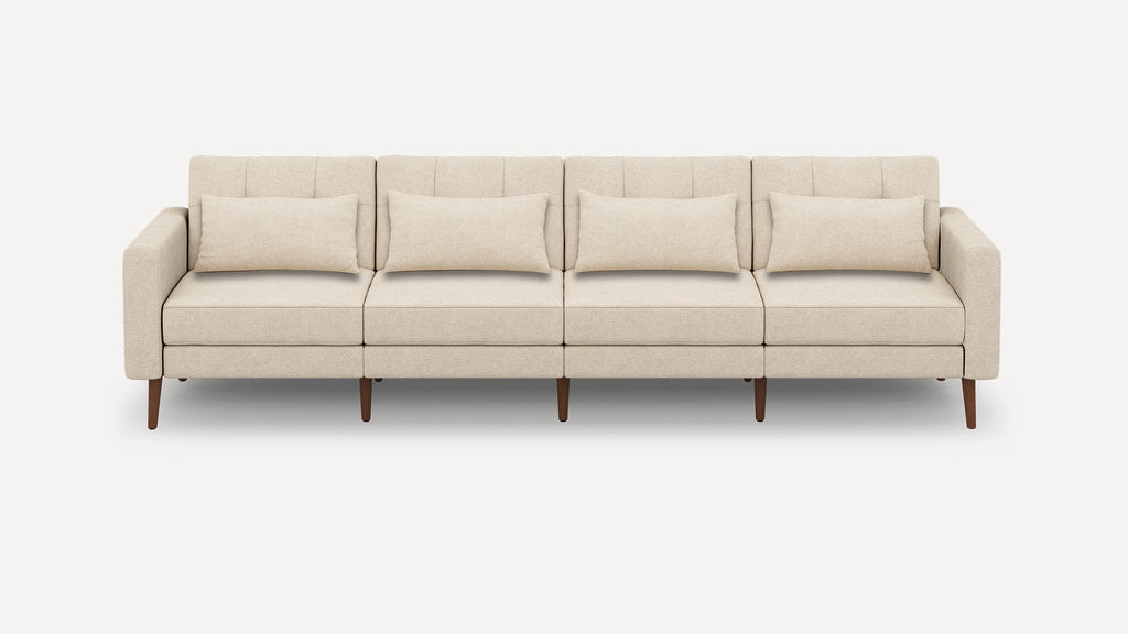 Modern beige four-seater sofa with rectangular cushions, clean lines, and wooden tapered legs on a plain white background.