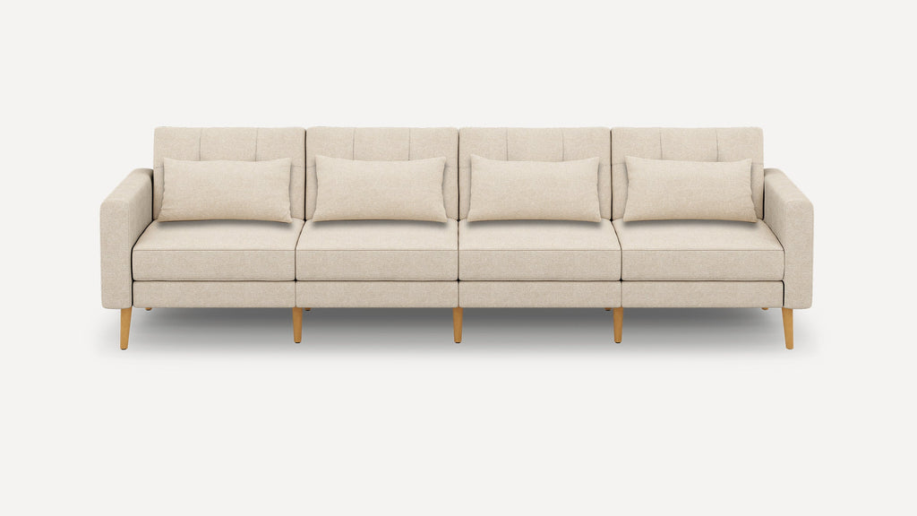 Beige four-seater modern sofa with wooden legs and four matching rectangular cushions on a plain white background.