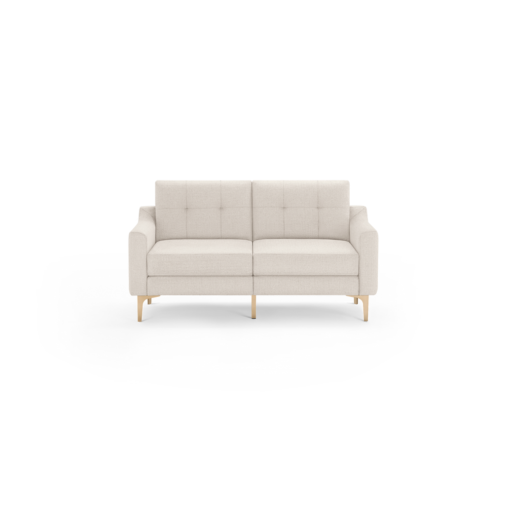 Modern two-seater beige fabric sofa with tufted back cushions, squared armrests, and light wooden legs on black background.