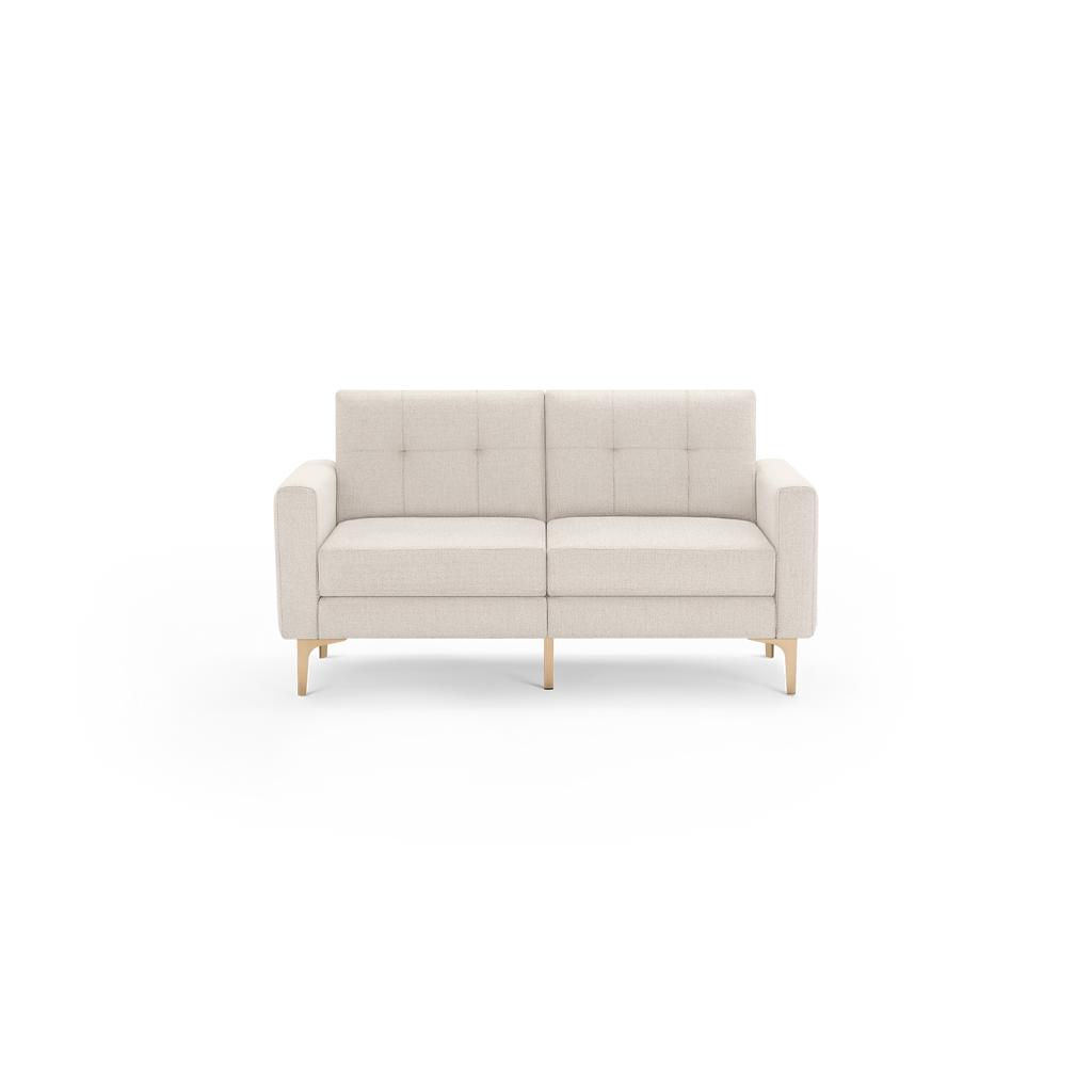 Modern beige fabric two-seater sofa with tufted backrest, square armrests, and light wooden legs against a transparent background.