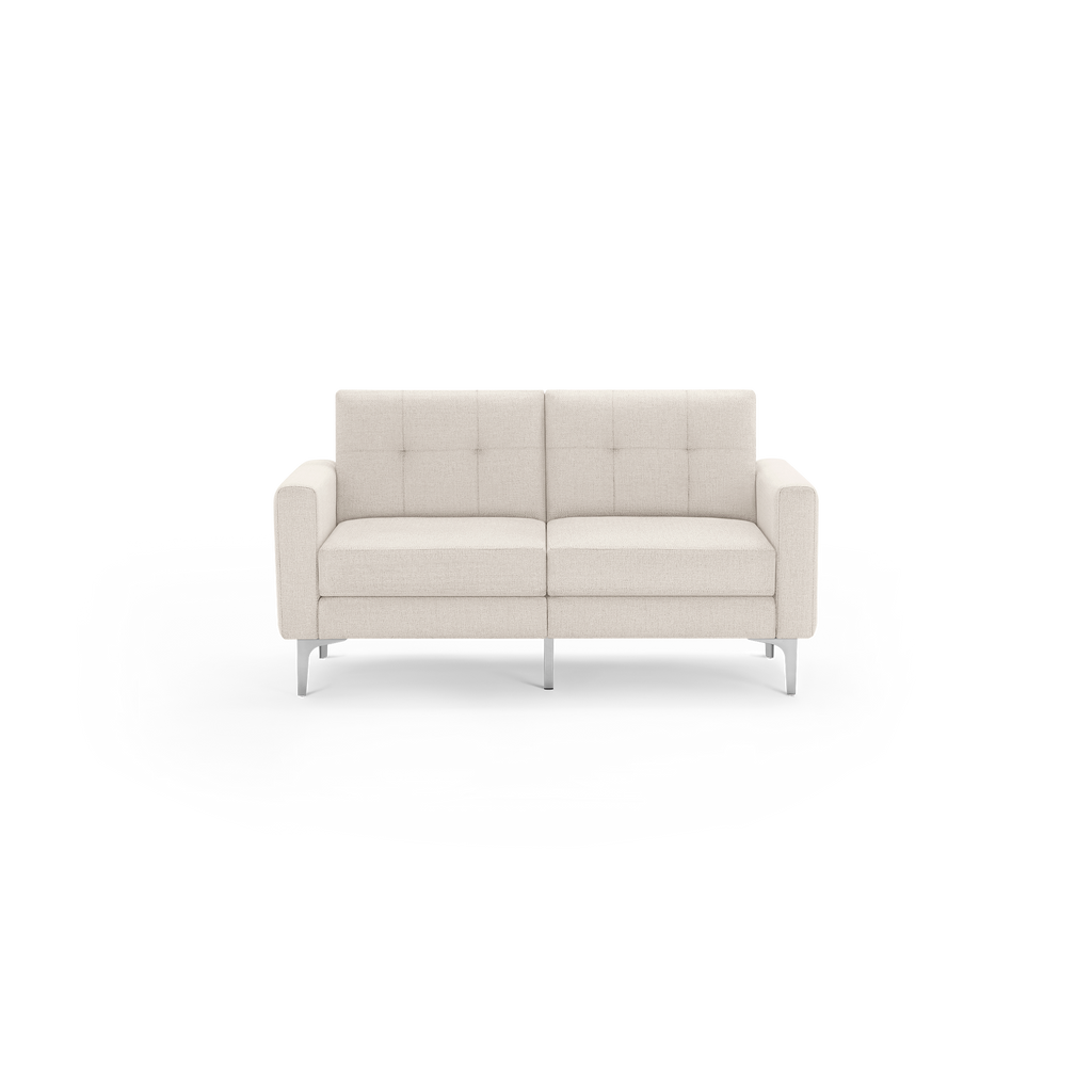 Modern two-seater sofa in light beige fabric with square tufted cushions, straight armrests, and slender silver metal legs.