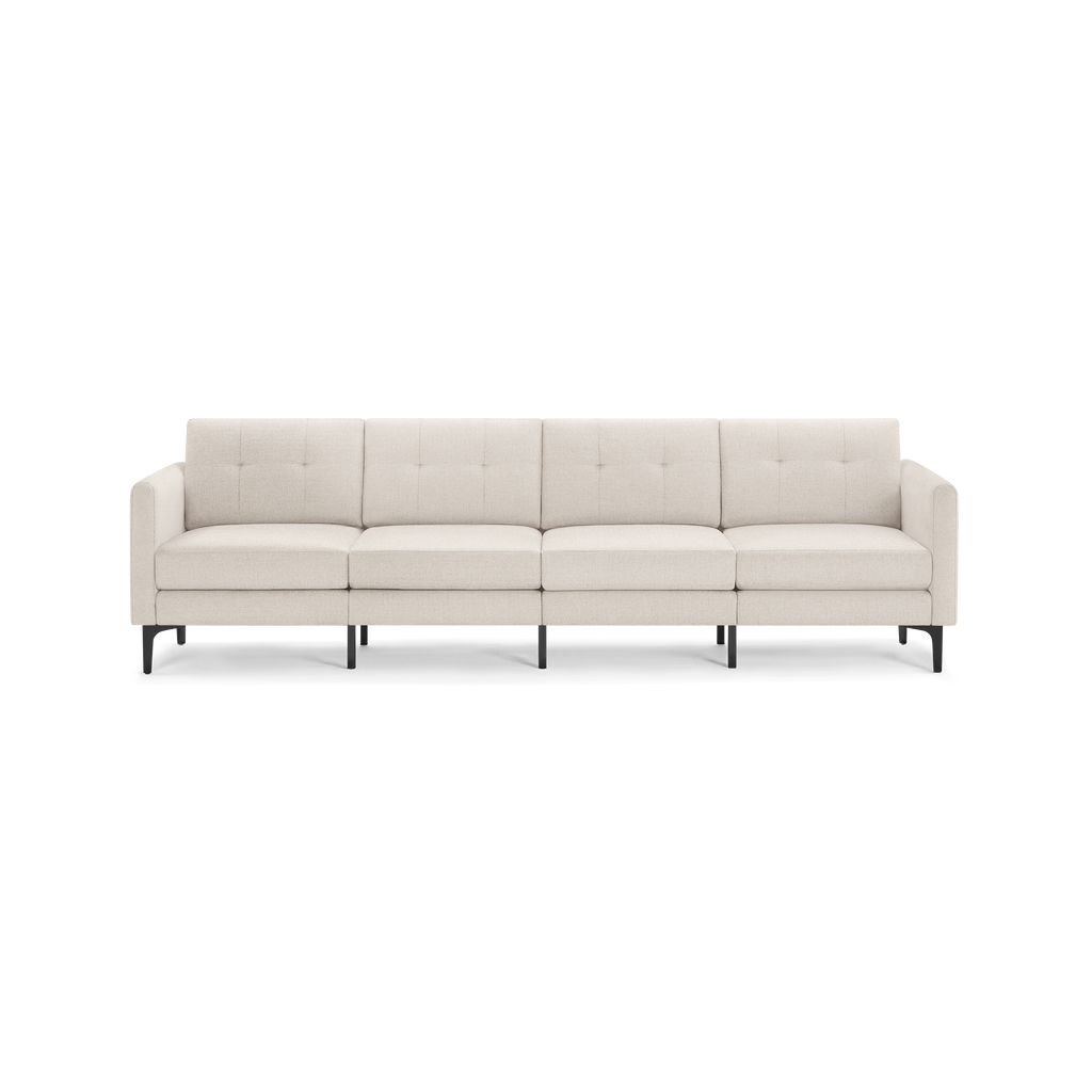 Modern beige four-seater sofa with tufted back cushions, slim armrests, and black metal legs on a white background.
