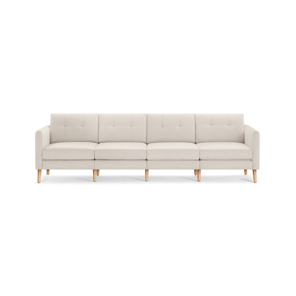 Beige four-seater sofa with tufted back cushions, clean lines, and light wooden legs, showcasing a modern minimalist design.