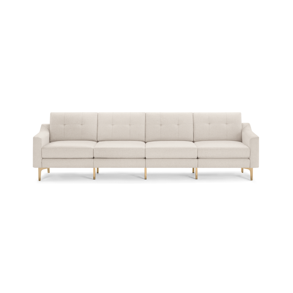 Modern four-seater beige fabric sofa with tufted back cushions and slim gold metal legs on a white background.