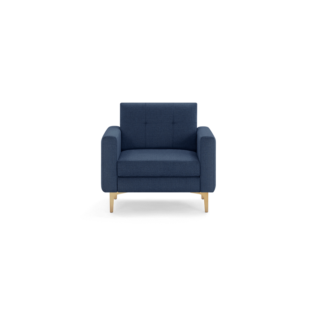 Modern navy blue single-seater armchair with wide armrests, tufted backrest, and light wooden legs, isolated on black background.