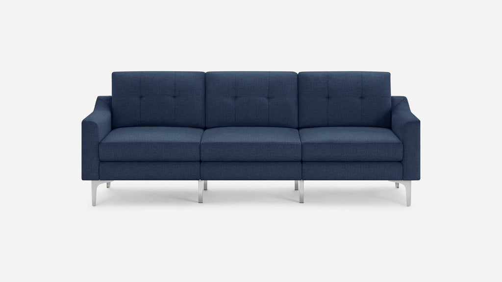 Three-seater modern navy blue upholstered sofa with button-tufted back cushions and slim metal legs on white background.