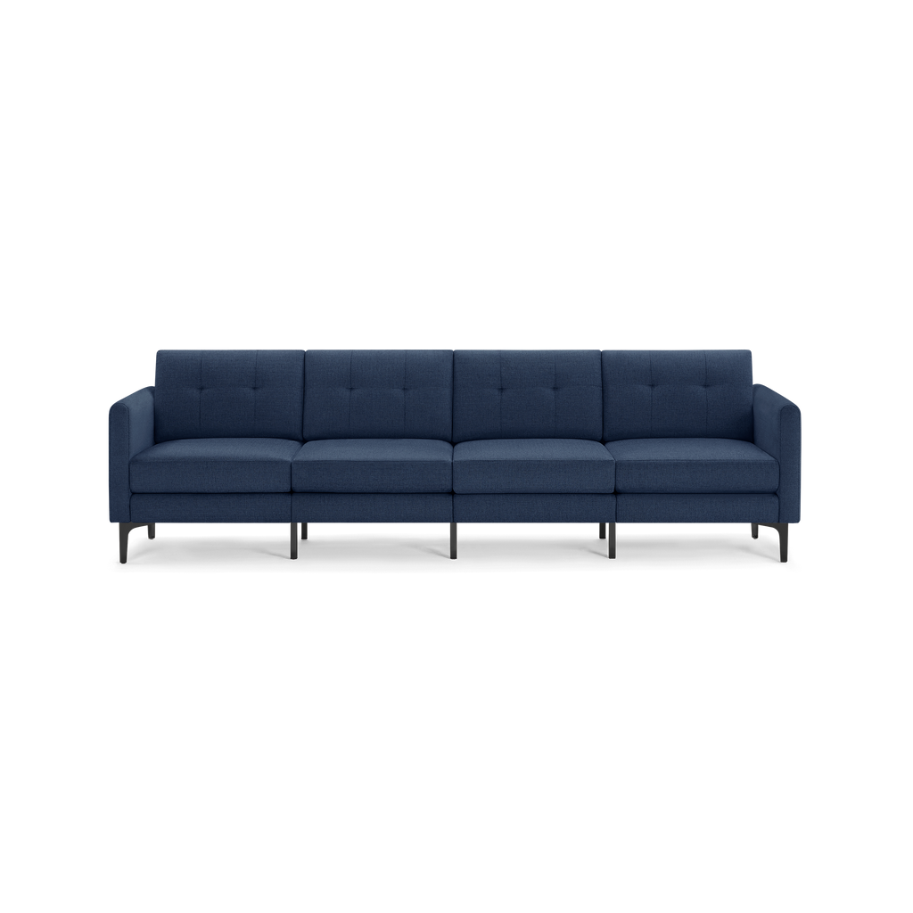 Modern navy blue four-seater sofa with tufted back cushions, squared arms, and black metal legs, isolated on black background.