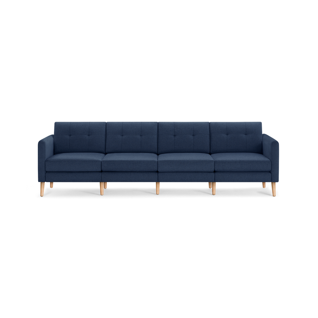 Four-seater modern navy blue fabric sofa with square tufted cushions and light wooden tapered legs.