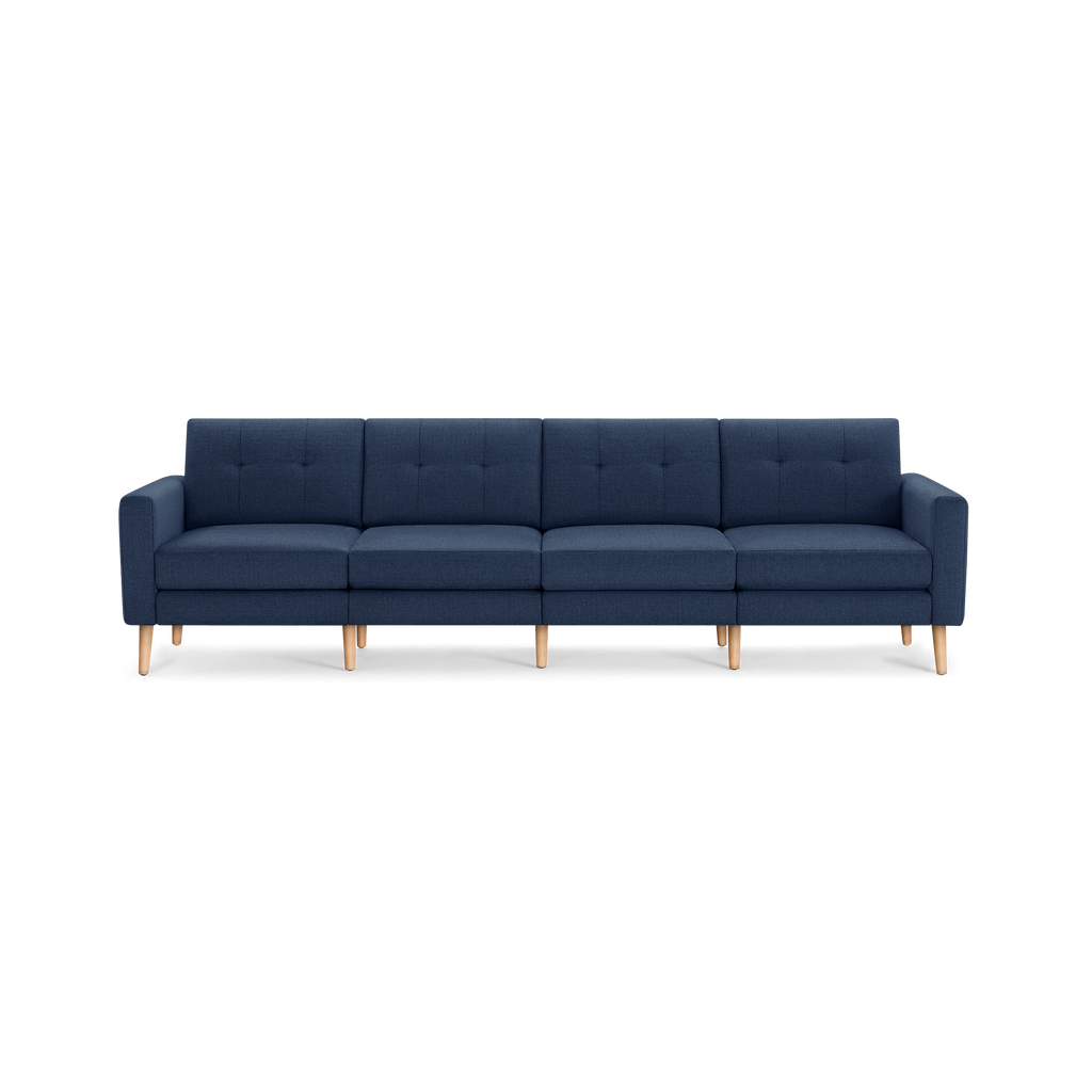 Modern navy blue four-seater sofa with tufted back cushions, wooden legs, and clean-lined armrests, designed for spacious living rooms.