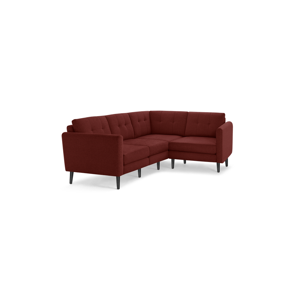 Modern L-shaped sectional sofa in dark red fabric with tufted back cushions and slim black legs, designed for corner seating.